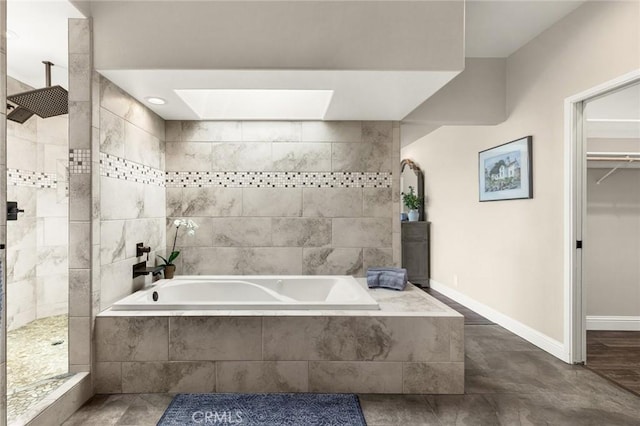 bathroom with a skylight, a garden tub, baseboards, and a walk in shower