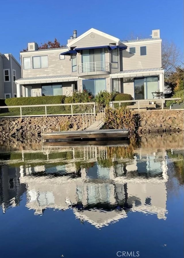 rear view of house featuring a chimney, a water view, and a balcony