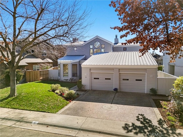 traditional-style home with metal roof, a garage, fence, driveway, and a front yard