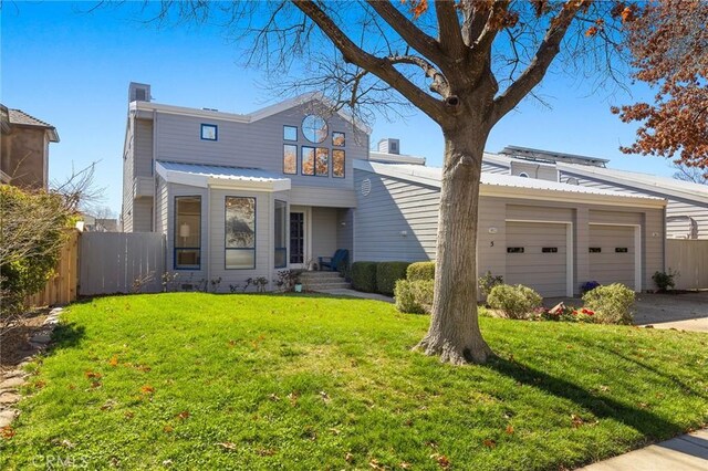 traditional home featuring a front lawn, an attached garage, concrete driveway, and fence