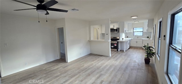 unfurnished living room featuring baseboards, light wood-style flooring, visible vents, and a sink