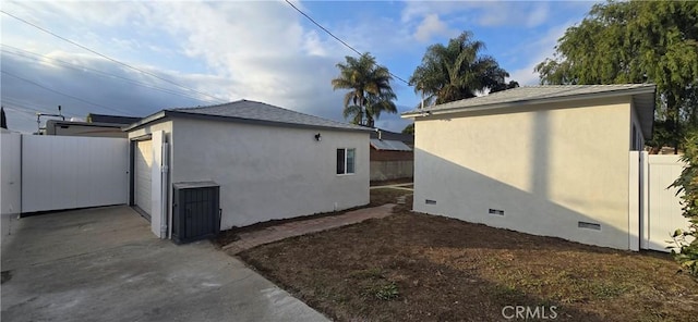 view of side of home featuring crawl space, fence, an outdoor structure, and stucco siding