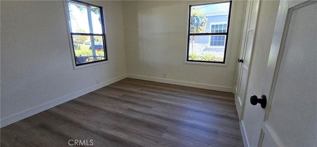 spare room with baseboards and dark wood finished floors