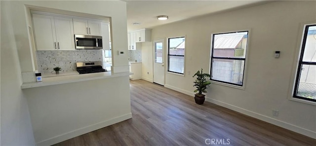 kitchen with appliances with stainless steel finishes, white cabinetry, backsplash, and baseboards