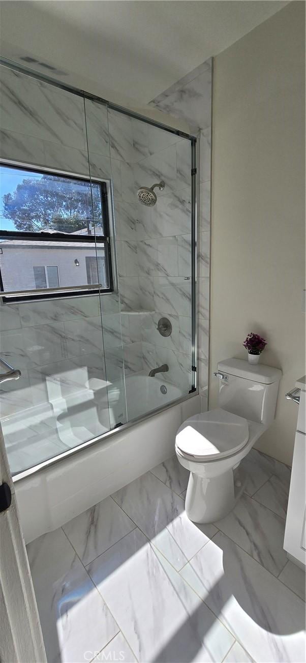 bathroom with toilet, marble finish floor, and enclosed tub / shower combo