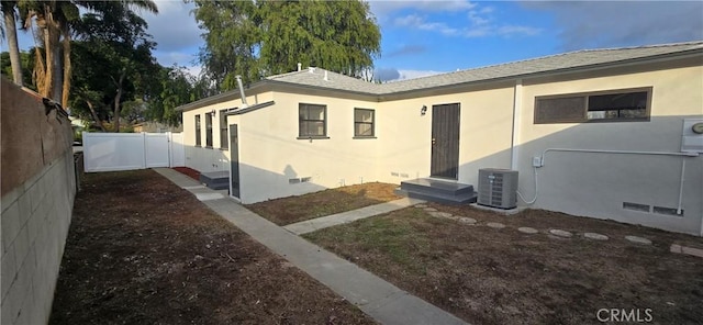 view of side of home with entry steps, central AC unit, a fenced backyard, crawl space, and stucco siding