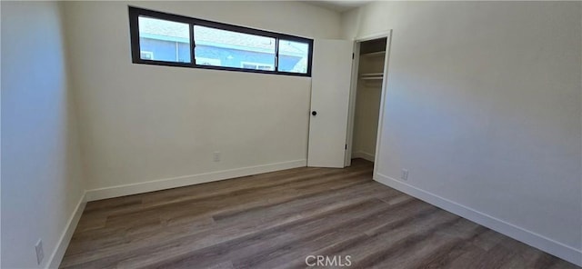 unfurnished bedroom with a closet, wood finished floors, and baseboards