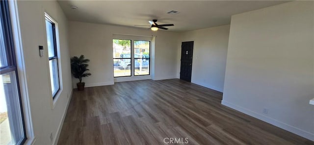 unfurnished room with dark wood-style floors, visible vents, baseboards, and ceiling fan