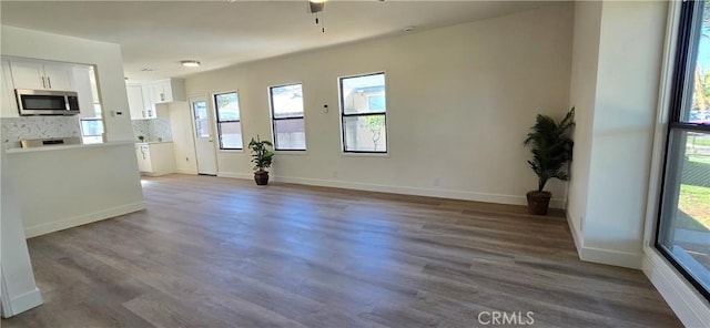 unfurnished living room with wood finished floors, a ceiling fan, and baseboards