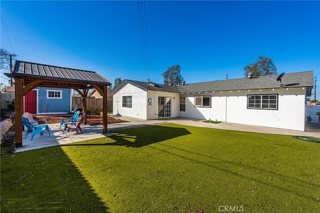 back of property with an outbuilding, fence, a yard, a patio area, and stucco siding