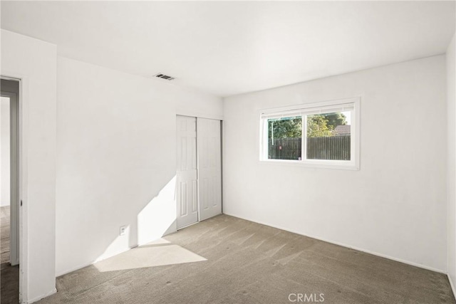 carpeted empty room featuring visible vents