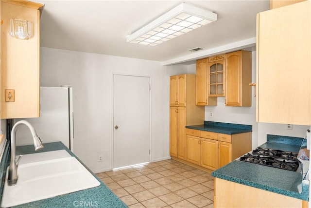 kitchen featuring visible vents, glass insert cabinets, stovetop, a sink, and light tile patterned flooring