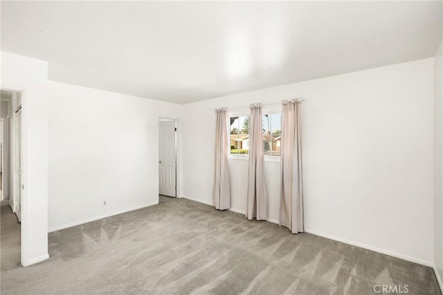 spare room featuring carpet floors and baseboards