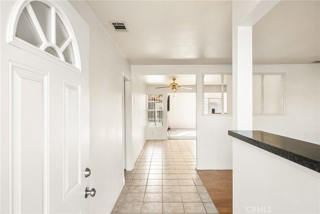 hall featuring light tile patterned floors and visible vents