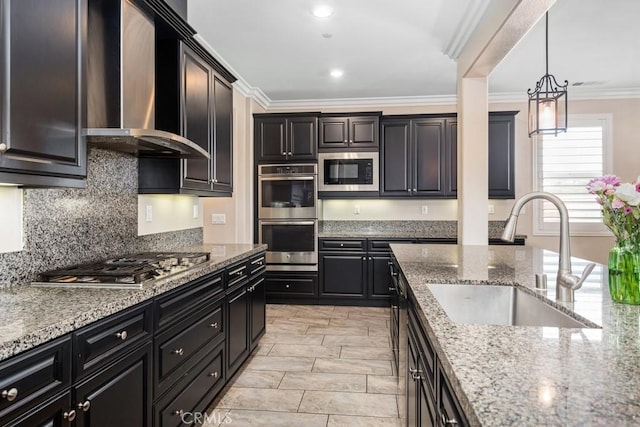 kitchen featuring light stone counters, ornamental molding, stainless steel appliances, wall chimney range hood, and a sink