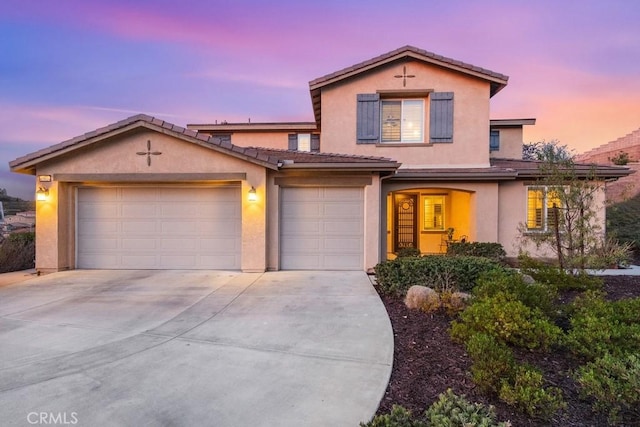 traditional-style house with an attached garage, a tiled roof, concrete driveway, and stucco siding