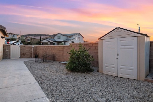 view of yard with a fenced backyard, a gate, an outdoor structure, and a shed