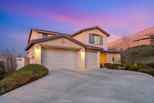 traditional-style house featuring a garage, concrete driveway, fence, and stucco siding