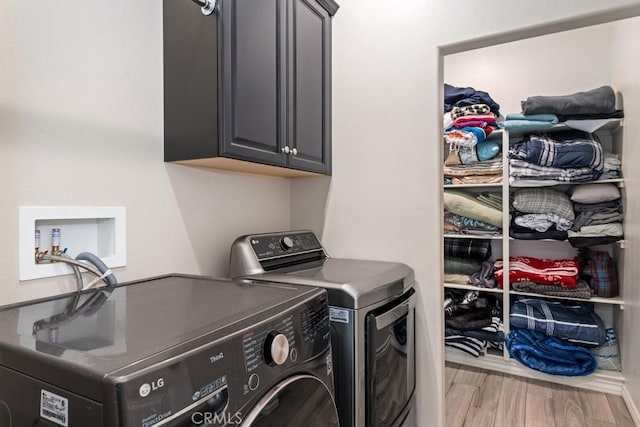 laundry room with cabinet space, washer and dryer, and wood finished floors