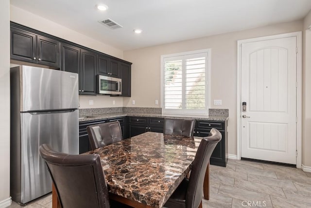 kitchen with a center island, recessed lighting, visible vents, appliances with stainless steel finishes, and dark stone countertops