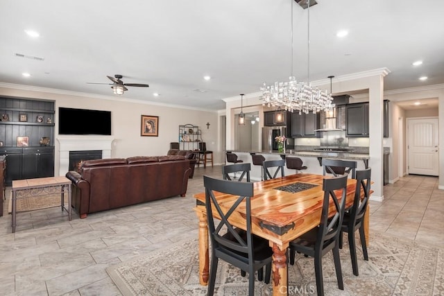 dining room with a ceiling fan, a warm lit fireplace, visible vents, and crown molding