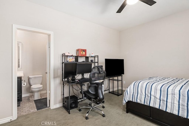 carpeted bedroom with ensuite bath, baseboards, and ceiling fan