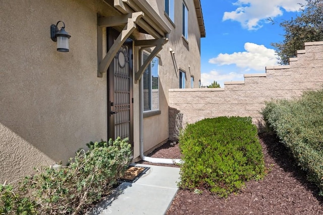 entrance to property with fence and stucco siding