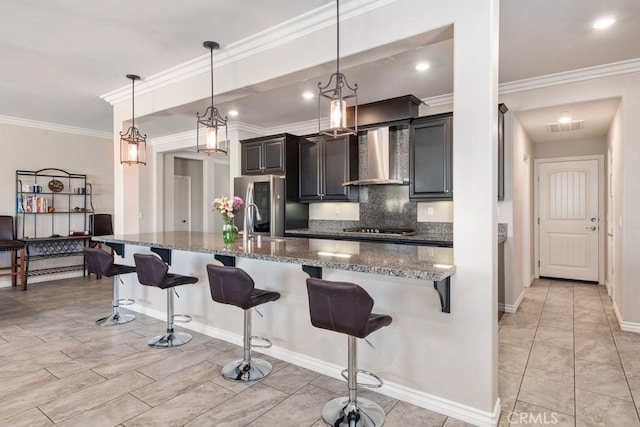 kitchen featuring wall chimney exhaust hood, a kitchen bar, visible vents, and stainless steel appliances