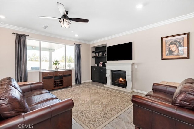 living area featuring ceiling fan, baseboards, crown molding, and a glass covered fireplace