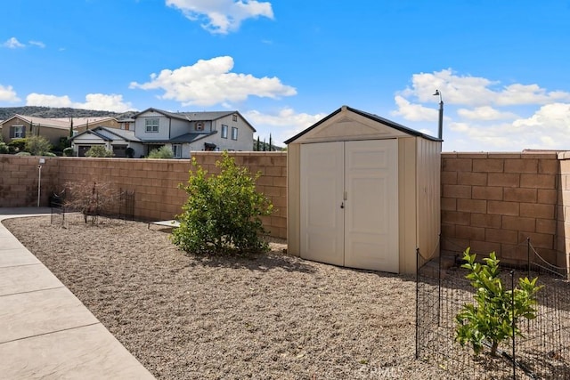 view of yard featuring a residential view, a fenced backyard, an outdoor structure, and a storage shed