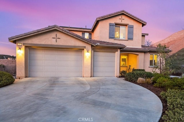 view of front of home featuring driveway, an attached garage, a tile roof, and stucco siding