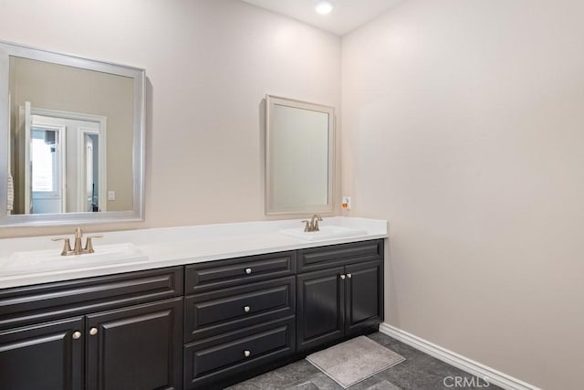 bathroom with double vanity, a sink, and baseboards