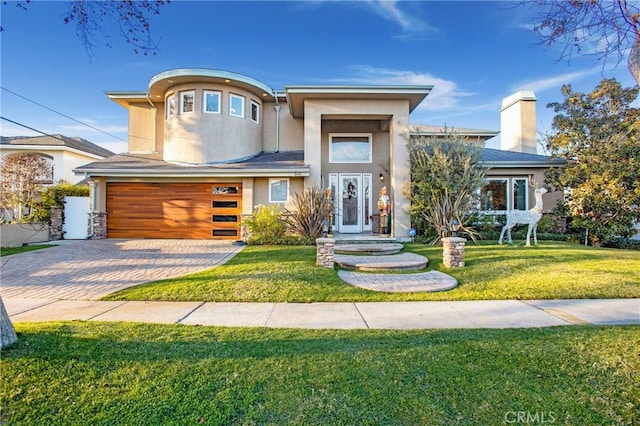 view of front of property with a garage, a front yard, decorative driveway, and stucco siding