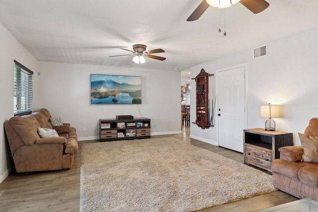 living area with baseboards, visible vents, ceiling fan, and wood finished floors