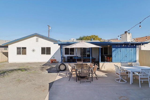 rear view of property with a patio, outdoor dining area, fence, and stucco siding