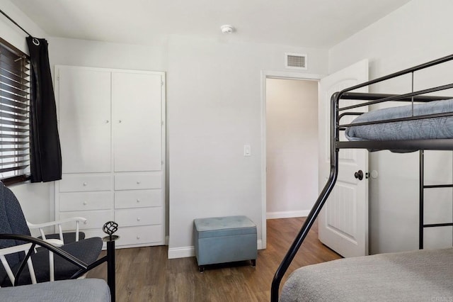 bedroom featuring a closet, wood finished floors, visible vents, and baseboards