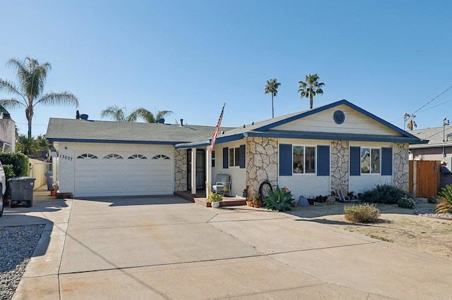 ranch-style house with stone siding, an attached garage, fence, and driveway