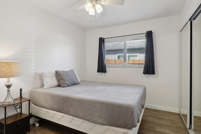 bedroom with a closet, wood finished floors, a ceiling fan, and baseboards