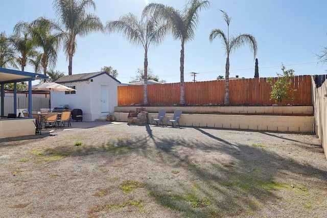 view of yard with a patio area, a fenced backyard, and an outdoor structure