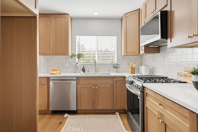 kitchen with stainless steel appliances, light countertops, a sink, and light wood finished floors