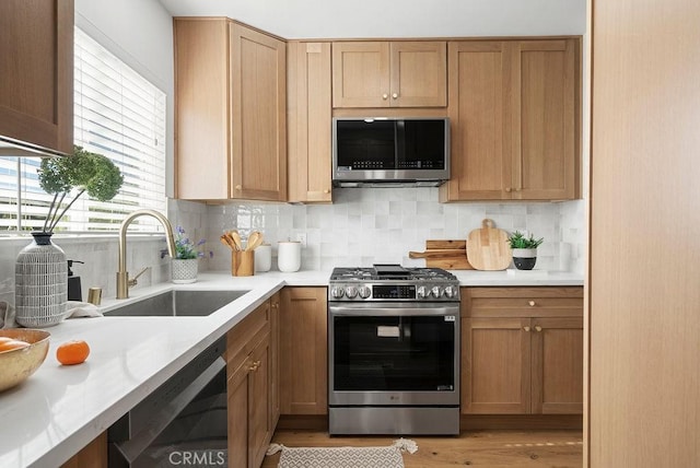 kitchen featuring backsplash, stainless steel appliances, a sink, and light countertops