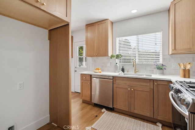 kitchen featuring decorative backsplash, appliances with stainless steel finishes, light countertops, and a sink