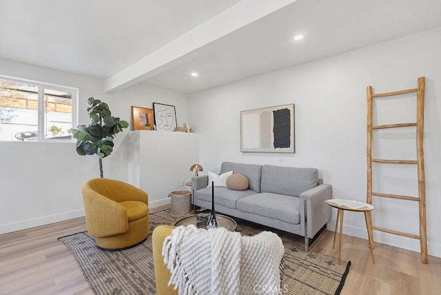 living area featuring baseboards, beamed ceiling, wood finished floors, and recessed lighting