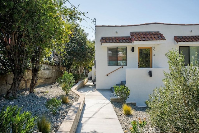 view of side of property featuring a fenced front yard, a tile roof, and stucco siding