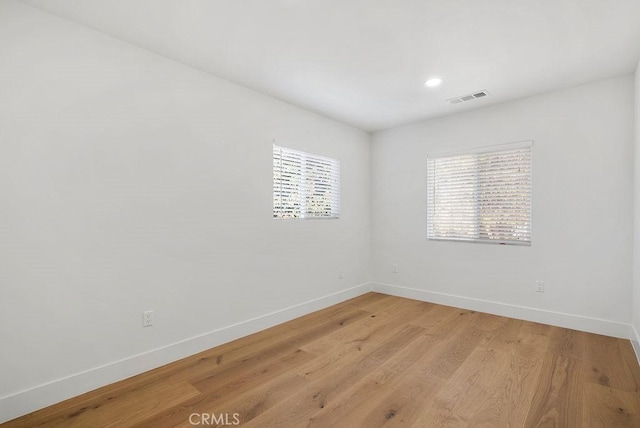 empty room with baseboards, visible vents, light wood-style flooring, and recessed lighting