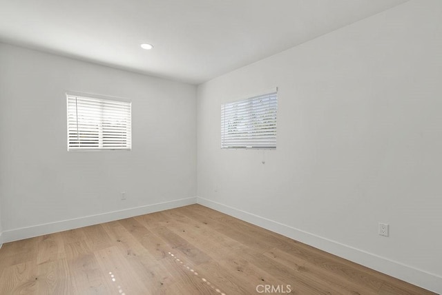 empty room with light wood finished floors, recessed lighting, a wealth of natural light, and baseboards