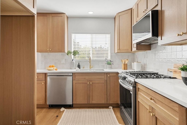 kitchen featuring appliances with stainless steel finishes, light countertops, a sink, and light wood finished floors