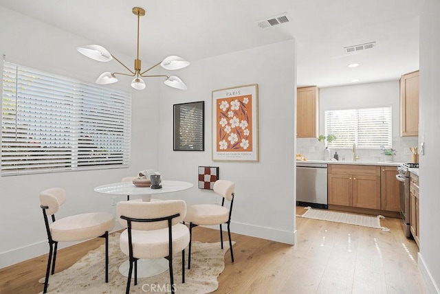 dining space with visible vents, a notable chandelier, and light wood-style flooring