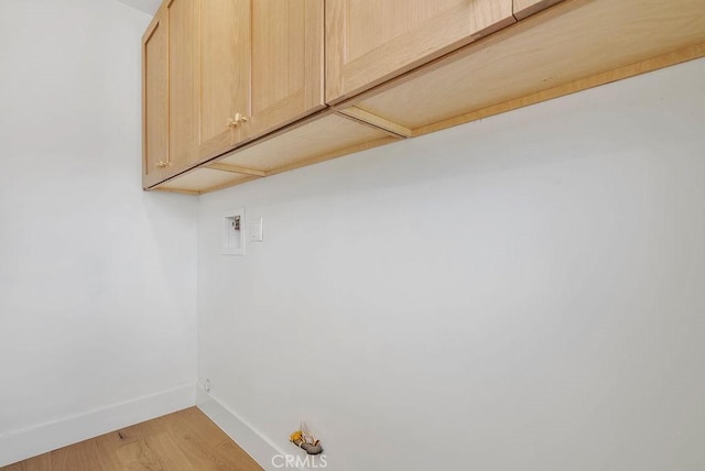 washroom featuring light wood finished floors, hookup for a washing machine, cabinet space, and baseboards