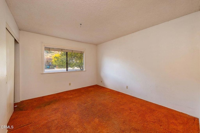 empty room featuring carpet and a textured ceiling